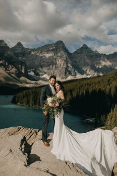 a bride and groom standing on top of a mountain