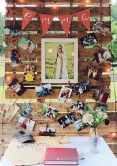 a table topped with pictures and books under string lights on top of a wooden structure