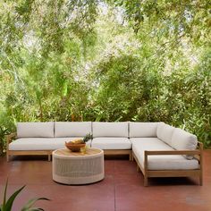 a couch and table on a patio with trees in the background