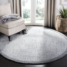 a large round rug in the middle of a living room with a chair and window