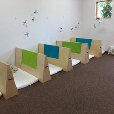 a row of wooden chairs sitting on top of carpeted floor next to a wall