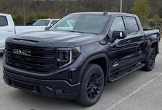 a black truck parked in a parking lot next to other cars and trucks behind it