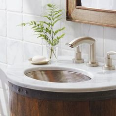 a bathroom sink sitting under a mirror next to a wooden barrel