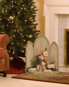 a christmas tree in the corner of a living room with two figurines and a fireplace