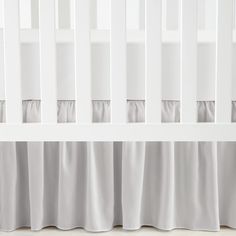 a baby crib with white sheets and curtains