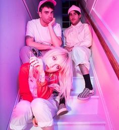 two young men sitting on the stairs with pink lighting