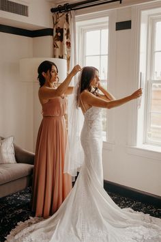 two bridesmaids helping each other get ready for their wedding