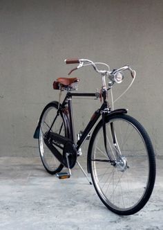 a black bicycle parked in front of a wall with no wheels on the back tire