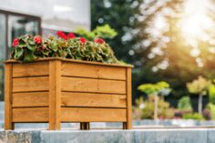 a wooden planter filled with red flowers