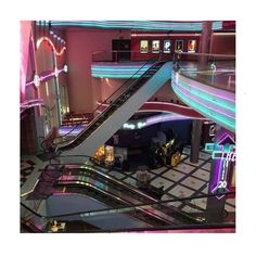 an escalator in a shopping mall with neon lights on the walls and stairs