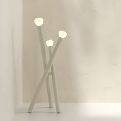 three white lights sitting next to each other on top of a table in front of a wall