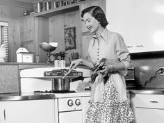 a woman is cooking in the kitchen with pots and pans on the stove top