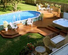 an above ground pool with decking and hot tub in the back yard, surrounded by lawn furniture