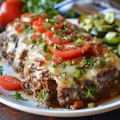 a white plate topped with meat covered in cheese and tomato slices next to green vegetables