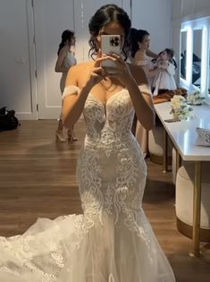 a woman in a wedding dress taking a selfie with her cell phone while standing in front of a mirror