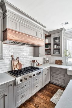 a kitchen with gray cabinets and white counter tops, wood flooring and an oven