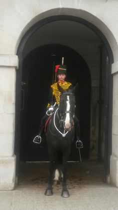 a man riding on the back of a black horse in front of a tunnel holding a flag