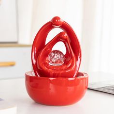 a red sculpture sitting on top of a white table next to a laptop computer and keyboard