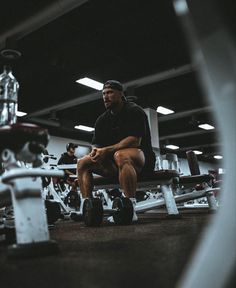 a man sitting on top of a bench in a gym next to dumbbells