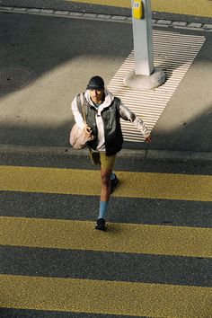 a man walking across a cross walk in the street