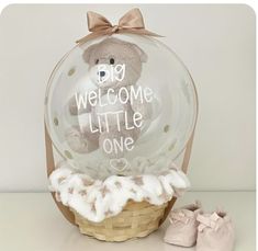 a teddy bear sitting in a basket with a welcome little one sign