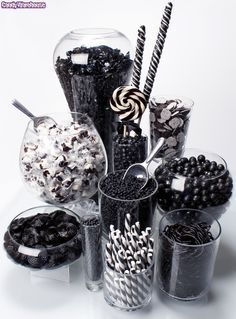 an assortment of candies and chocolates in glass containers on a white table top