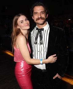 a man in a tuxedo standing next to a woman