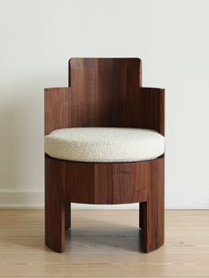 a wooden chair sitting on top of a hard wood floor next to a white wall