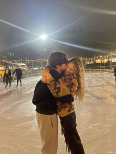 a man and woman hugging on an ice rink