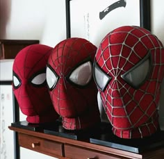 three spider - man masks sitting on top of a dresser