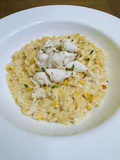 a white plate topped with rice and chicken on top of a wooden table next to a fork