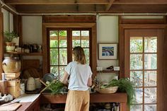 a woman standing in a kitchen preparing food on top of a wooden counter next to an open window