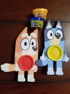 two plastic toys sitting on top of a wooden table