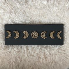 the five phases of the moon are shown in gold on a black plaque with white fur