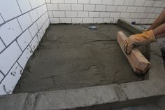 a man laying cement on top of a floor