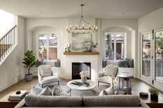 a living room filled with furniture and a fire place in front of a window next to a stair case