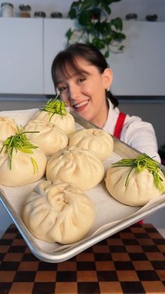 a woman holding a tray full of dumplings