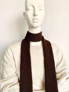 a white mannequin wearing a brown knitted scarf on top of it's head