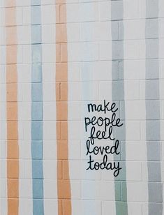 the words make people feel loved today are painted on a wall with multicolored stripes