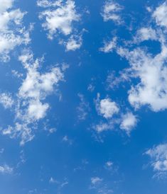 an airplane is flying in the blue sky with white clouds above it on a sunny day