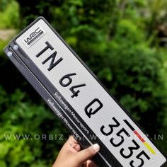 a person holding up a white and black license plate