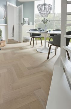 an open living room and dining area with wood flooring, white walls and furniture