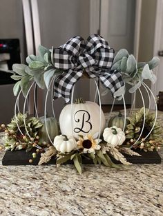 a pumpkin decorated with greenery and a monogrammed bow sits on a table