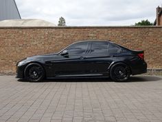 a black car parked in front of a brick wall