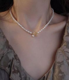 This elegant freshwater pearl necklace features rice-shape classic and modern design elements. The necklace showcases two different-sized small, lustrous freshwater pearls, arranged in a delicate sequence to accentuate the neckline. A standout feature is the bold gold toggle clasp, positioned at the front for a contemporary twist, complemented by a charming, larger pearl drop that adds a refined yet playful touch. Pearl Necklace With Gold, Beaded Toggle Clasp, Toggle Clasp Necklace, Clasp Necklace, Freshwater Pearl Necklace, Pearl Shell, Freshwater Pearl Necklaces, Toggle Clasp, Pearl Drop