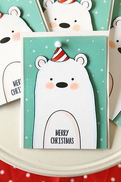 four polar bear christmas cards sitting on top of a white plate with red and green decorations