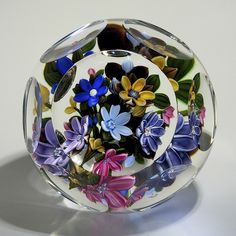 a glass bowl filled with colorful flowers on top of a table