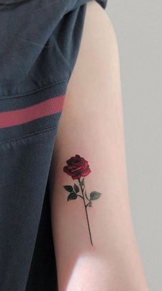 a woman's arm with a single red rose tattoo on the left inner arm