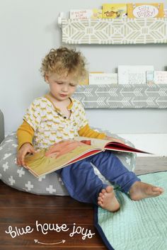 a little boy sitting on a bean bag chair reading a book with the words blue house jogs