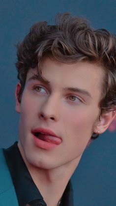 a close up of a person wearing a suit and tie with his tongue sticking out